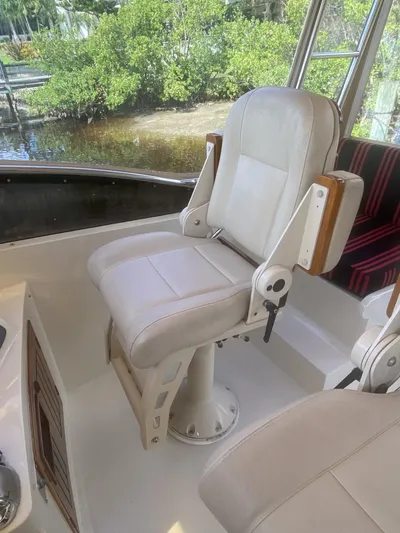 Sirena Yacht Photos Pics Captain's chair on 1986 Midnight Lace 52 Flybridge yacht, featuring white upholstery and wooden accents.