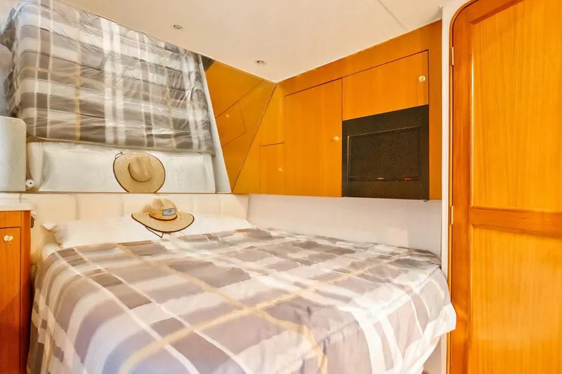  Yacht Photos Pics Cozy bedroom in 1999 Ocean Yachts 48 Super Sport with plaid bedding and wooden cabinetry.