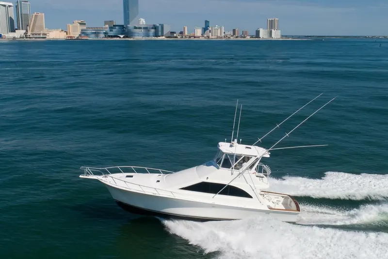  Yacht Photos Pics 1999 Ocean Yachts 48 Super Sport cruising on ocean near city skyline.