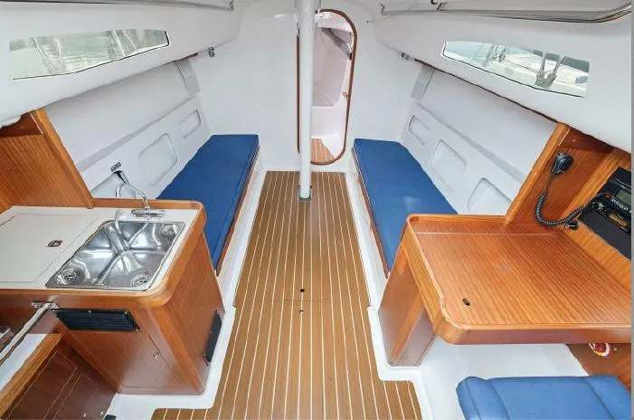 J/111 Yacht Photos Pics 2013 J Boats J/111 interior with wood finish, blue seating, and compact kitchen area.