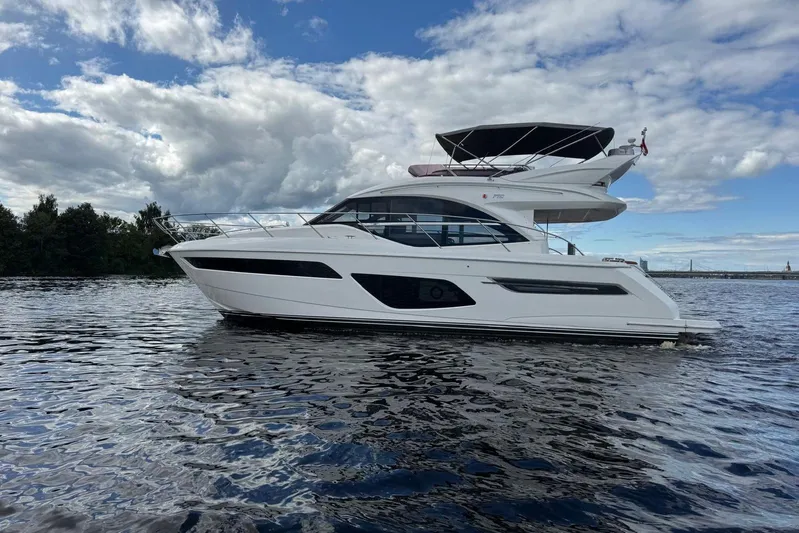  Yacht Photos Pics Luxury 2022 Princess F50 yacht cruising on a serene waterway under a cloudy sky.