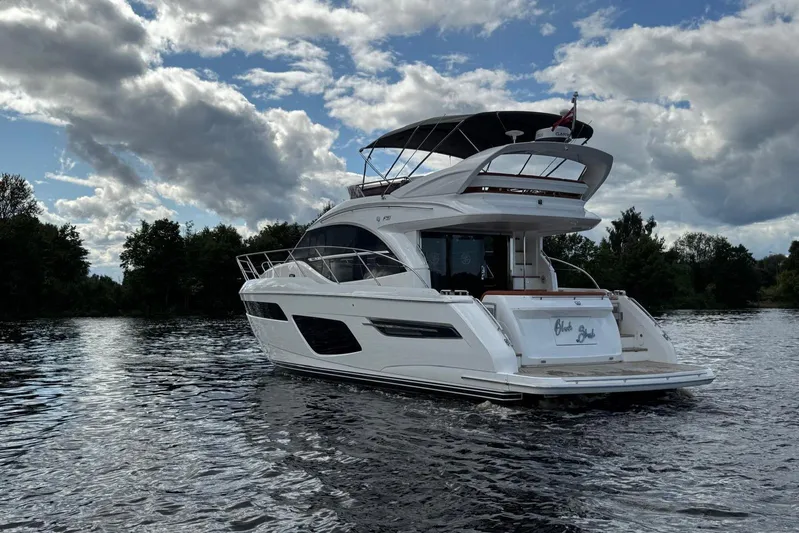  Yacht Photos Pics Luxurious 2022 Princess F50 yacht cruising on a serene lake under a cloudy sky.