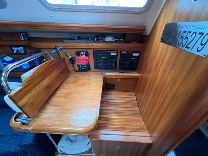  Yacht Photos Pics Navigation station on a 2004 Hunter 41 sailboat with control panels and wooden finish.