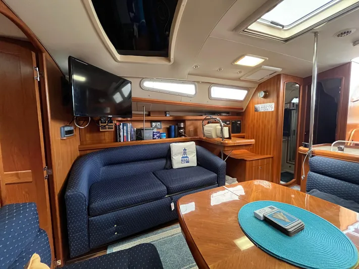  Yacht Photos Pics Interior of 2004 Hunter 41 yacht with blue seating, wooden finishes, and a mounted TV.