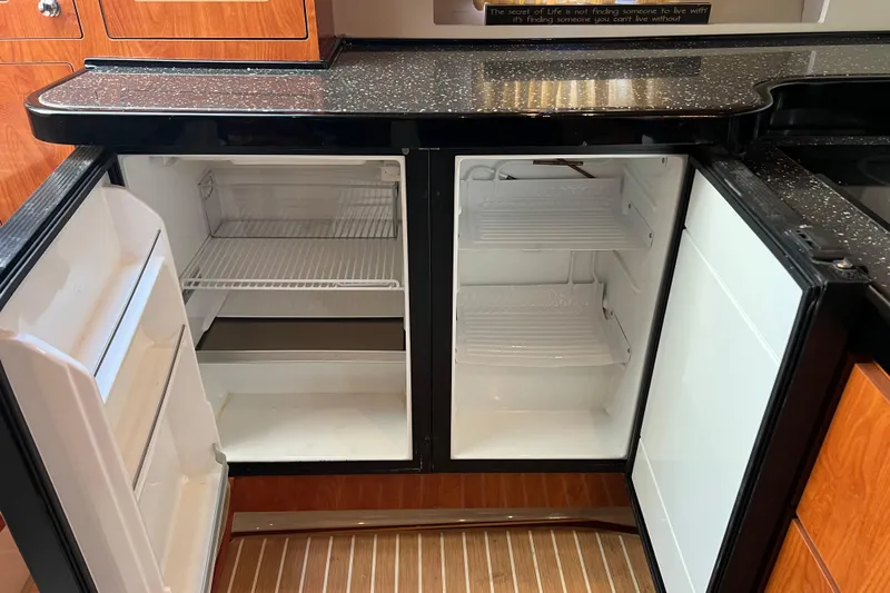 Belle Journee Yacht Photos Pics 2008 Four Winns V378 yacht kitchen with open refrigerator, black countertop, and wooden cabinetry.