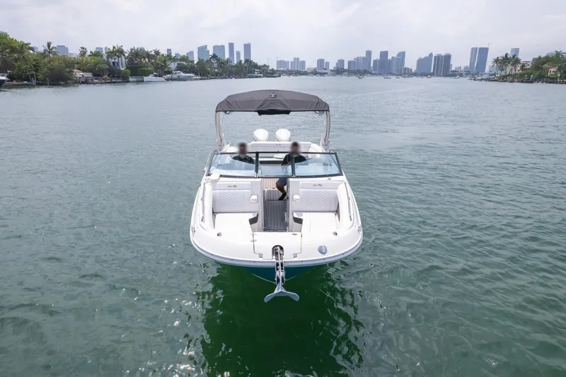  Yacht Photos Pics 2022 Sea Ray SDX 290 Outboard cruising on a calm waterway with city skyline backdrop.
