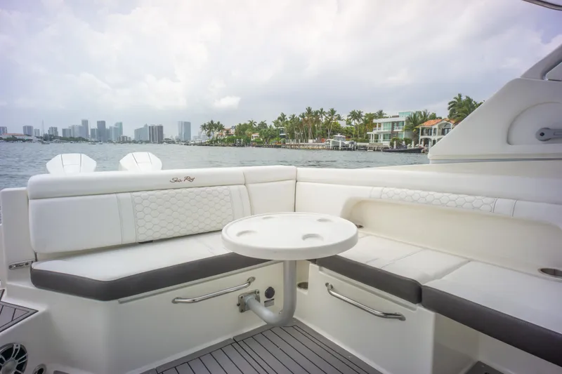  Yacht Photos Pics 2022 Sea Ray SDX 290 Outboard boat interior with seating and table, overlooking waterfront homes.