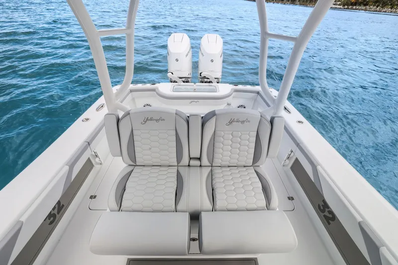  Yacht Photos Pics 2026 Yellowfin 32 Offshore boat interior with cushioned seating and twin engines on blue water.