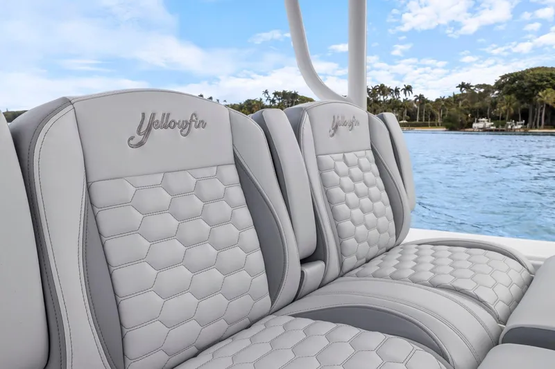  Yacht Photos Pics 2026 Yellowfin 32 Offshore boat seats with hexagonal pattern, overlooking serene water and lush greenery.