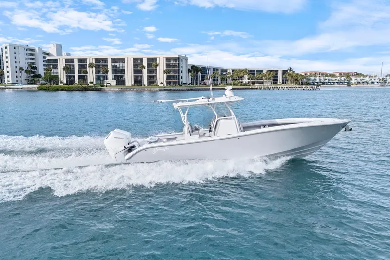  Yacht Photos Pics 2026 Yellowfin 32 Offshore boat cruising on blue water near modern buildings.