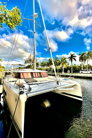 Scarlet Ibis Yacht Photos Pics 2023 Fountaine Pajot Isla 40 catamaran docked by palm trees under a vibrant sky.