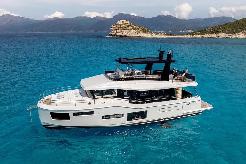  Yacht Photos Pics 2026 Beneteau Grand Trawler 63 yacht cruising in clear blue waters, scenic coastal backdrop.