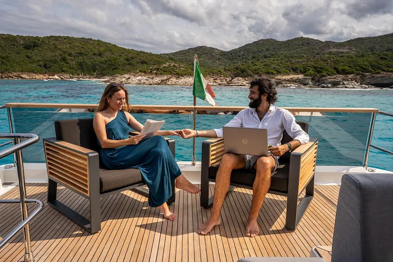  Yacht Photos Pics Couple relaxing on 2026 Beneteau Grand Trawler 63 yacht, enjoying scenic ocean view.