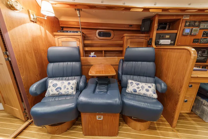 Firelight Yacht Photos Pics Luxurious interior of 1999 Catalina 470 yacht with blue leather chairs and wooden accents.