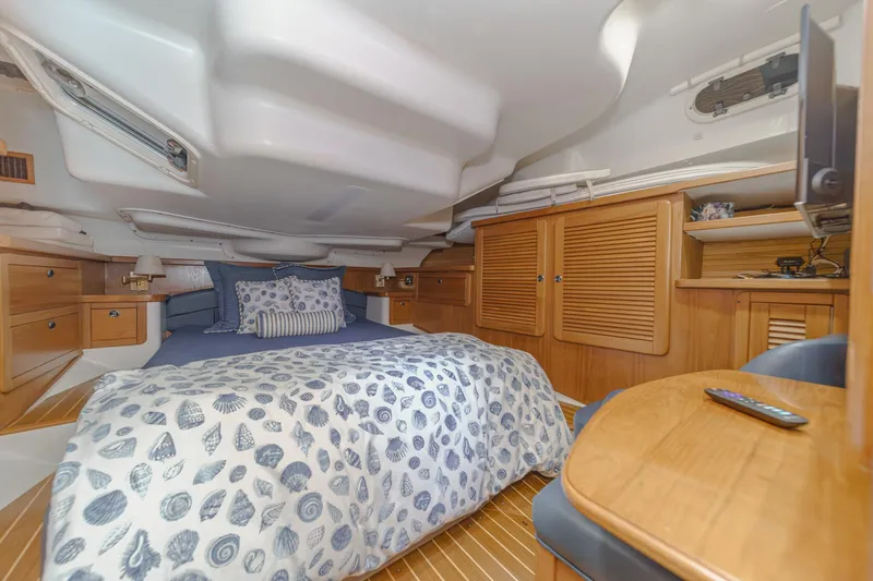 Firelight Yacht Photos Pics Cozy cabin interior of 1999 Catalina 470 sailboat with bed, wooden cabinets, and nautical decor.