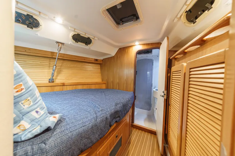 Firelight Yacht Photos Pics Cozy cabin interior of 1999 Catalina 470 sailboat with wooden finishes and blue bedding.