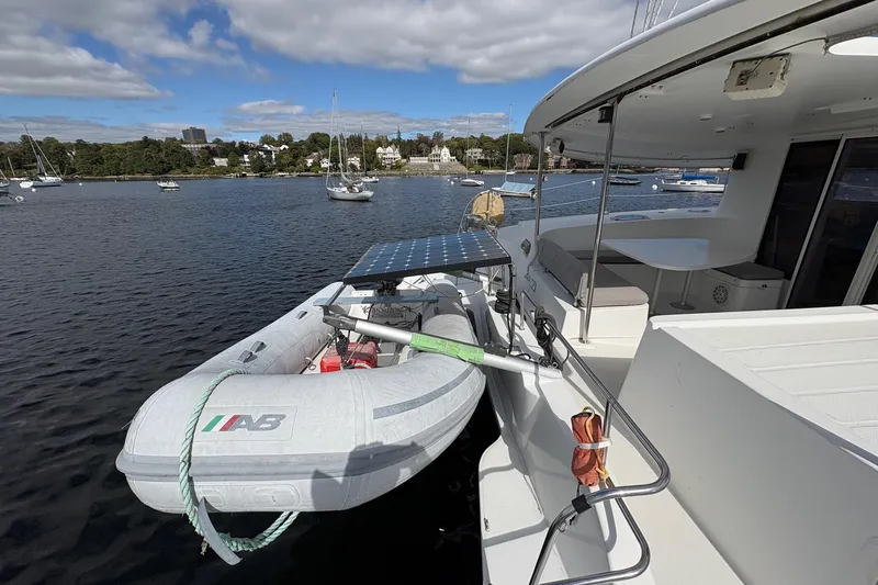 Littlest Hobo Yacht Photos Pics 2009 Fountaine Pajot Orana 44 Maestro catamaran with dinghy and solar panel, moored in scenic harbor.