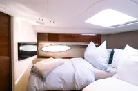 Luxurious cabin interior of 2016 Princess V48 Open yacht, featuring cozy bedding and modern design.