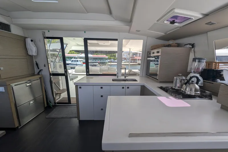 Love A Fayre Yacht Photos Pics Modern kitchen interior of 2020 Fountaine Pajot Astrea 42 catamaran, featuring sleek appliances and ample counter space.