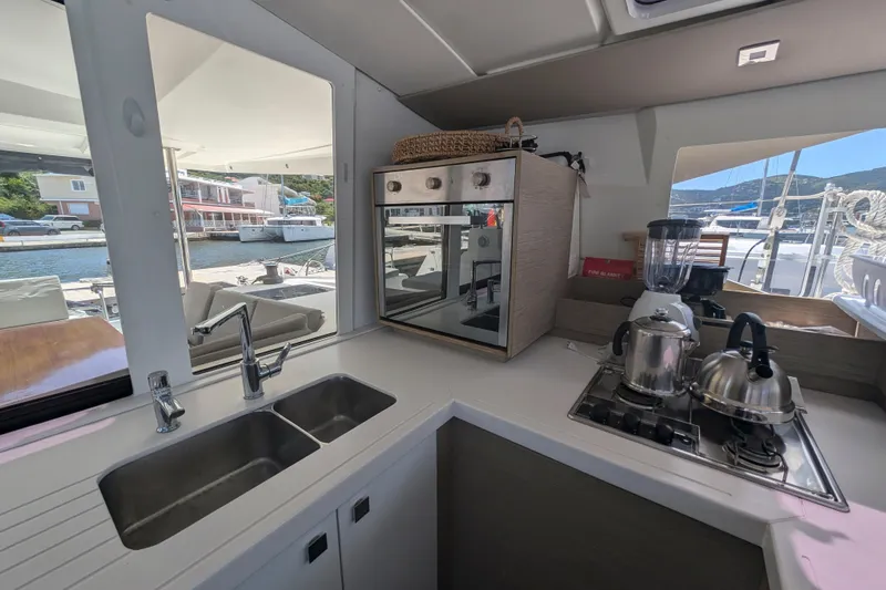 Love A Fayre Yacht Photos Pics Modern kitchen interior on 2020 Fountaine Pajot Astrea 42 catamaran, featuring sleek appliances and marina view.