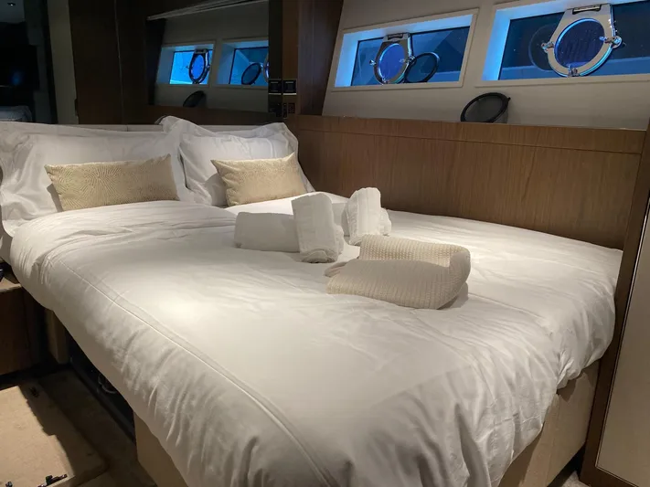 Kayra 1 Yacht Photos Pics Luxurious bedroom interior of 2024 Ferretti Yachts 780 with elegant bedding and porthole windows.