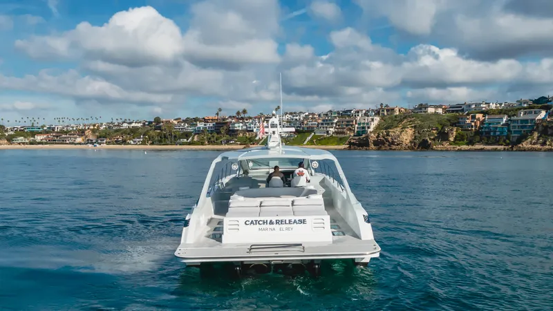 Catch And Release Yacht Photos Pics Triton Custom 2017 boat cruising near coastal town under cloudy sky.