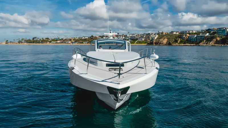 Catch And Release Yacht Photos Pics Triton Custom 2017 boat on calm water with coastal background and cloudy sky.