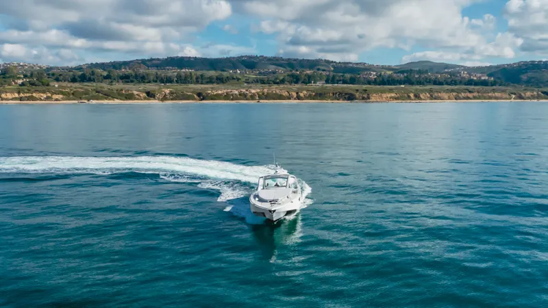 Catch And Release Yacht Photos Pics Triton Custom 2017 boat cruising on calm ocean with scenic coastline backdrop.