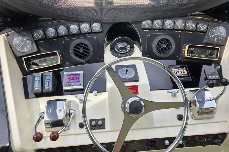 Hatt Trick Yacht Photos Pics Control panel of a 1990 Hatteras 52 Cockpit Motor Yacht with gauges and steering wheel.