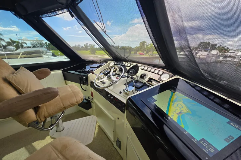 Hatt Trick Yacht Photos Pics 1990 Hatteras 52 Cockpit Motor Yacht helm with navigation screen and plush captain's chair.