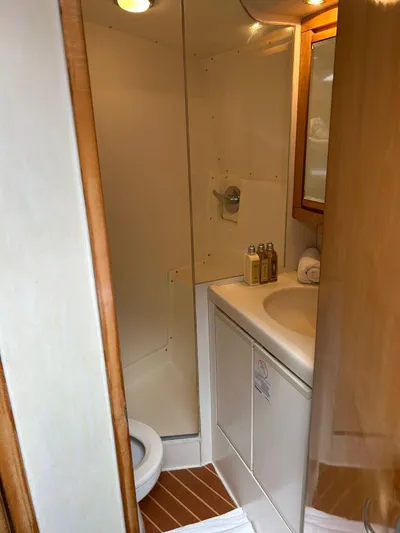 El Caiman Yacht Photos Pics Bathroom interior of 1994 Bertram 46 Moppie yacht, featuring shower, sink, and toiletries.