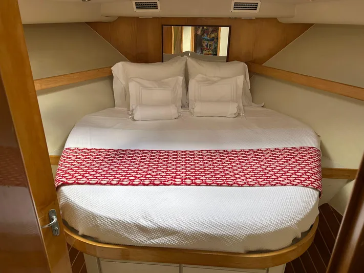 El Caiman Yacht Photos Pics Cozy cabin interior of 1994 Bertram 46 Moppie with neatly arranged bed and red accent.