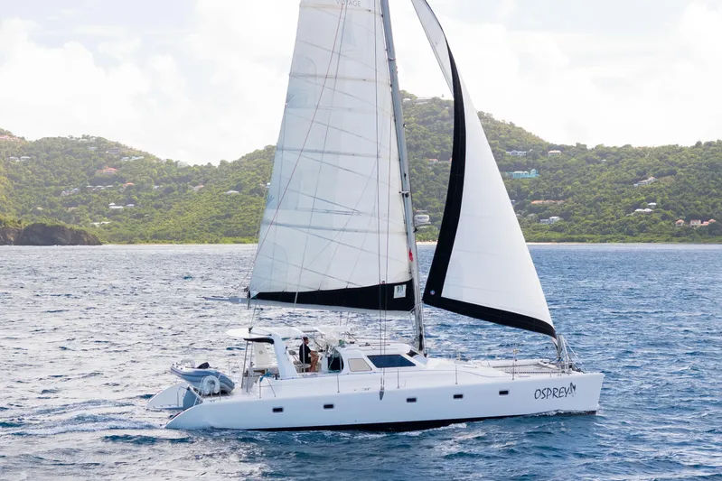 Osprey Yacht Photos Pics Sailing catamaran Voyage 520, 2010 model, cruising near lush green coastline.