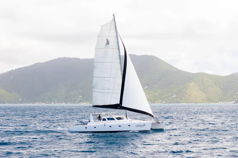 Osprey Yacht Photos Pics Sailing catamaran Voyage 520, 2010 model, cruising near lush green mountains.