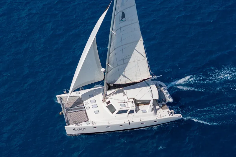 Osprey Yacht Photos Pics Aerial view of 2010 Voyage 520 catamaran sailing on clear blue ocean.