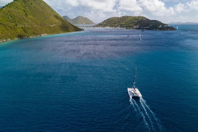 Osprey Yacht Photos Pics Catamaran sailing in clear blue waters near lush green islands, Voyage 520, 2010 model.