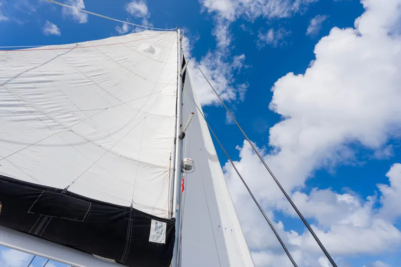 Osprey Yacht Photos Pics Sail of a 2010 Voyage 520 yacht against a bright blue sky with clouds.