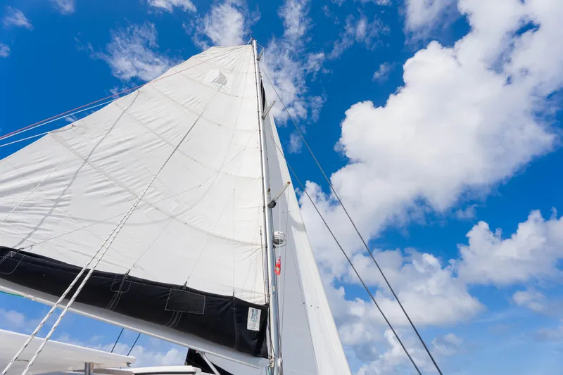 Osprey Yacht Photos Pics Sail of a 2010 Voyage 520 yacht against a bright blue sky with clouds.