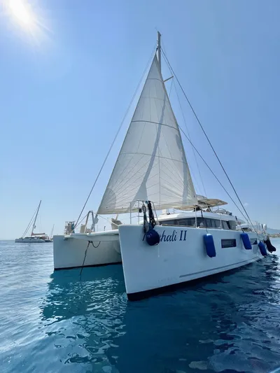  Yacht Photos Pics 2018 Lagoon 620 catamaran sailing on clear blue water under a sunny sky.