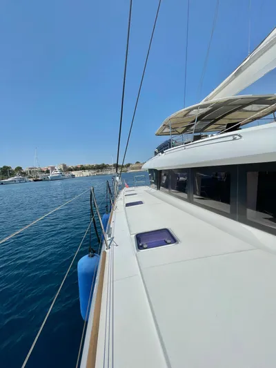  Yacht Photos Pics 2018 Lagoon 620 yacht on calm blue waters, clear sky, side deck view.