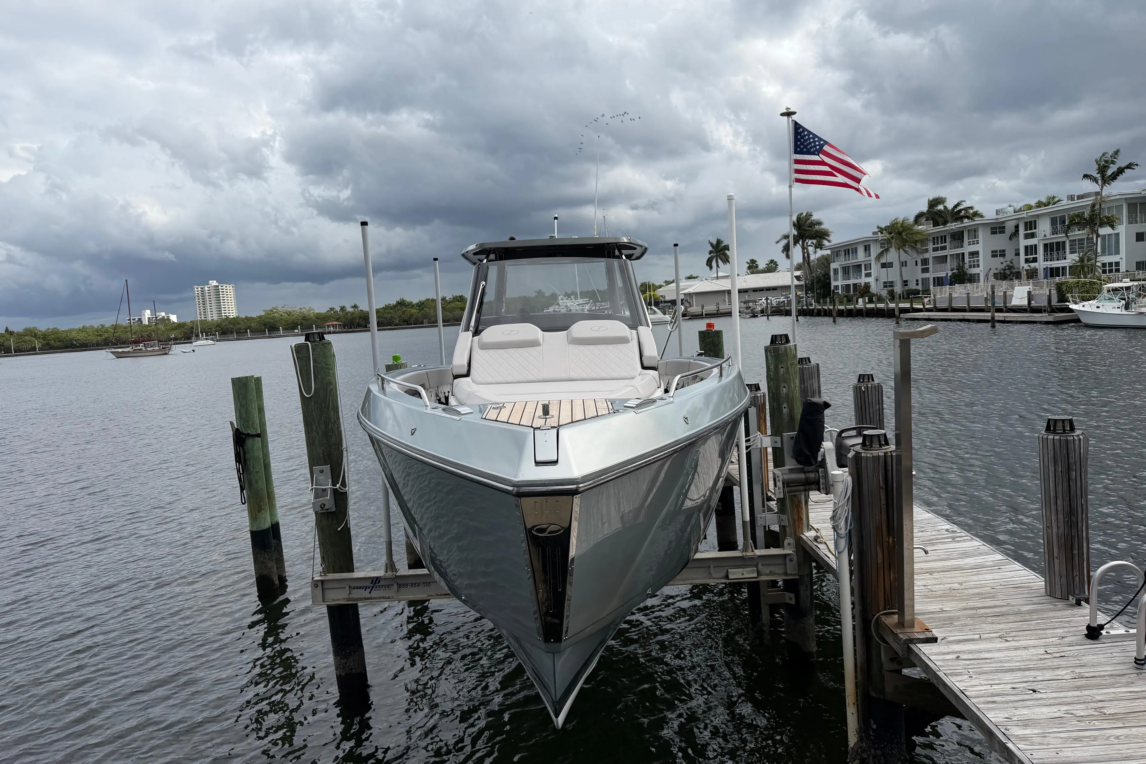 2023 Schaefer V33 boat docked, cloudy sky, American flag, waterfront buildings.