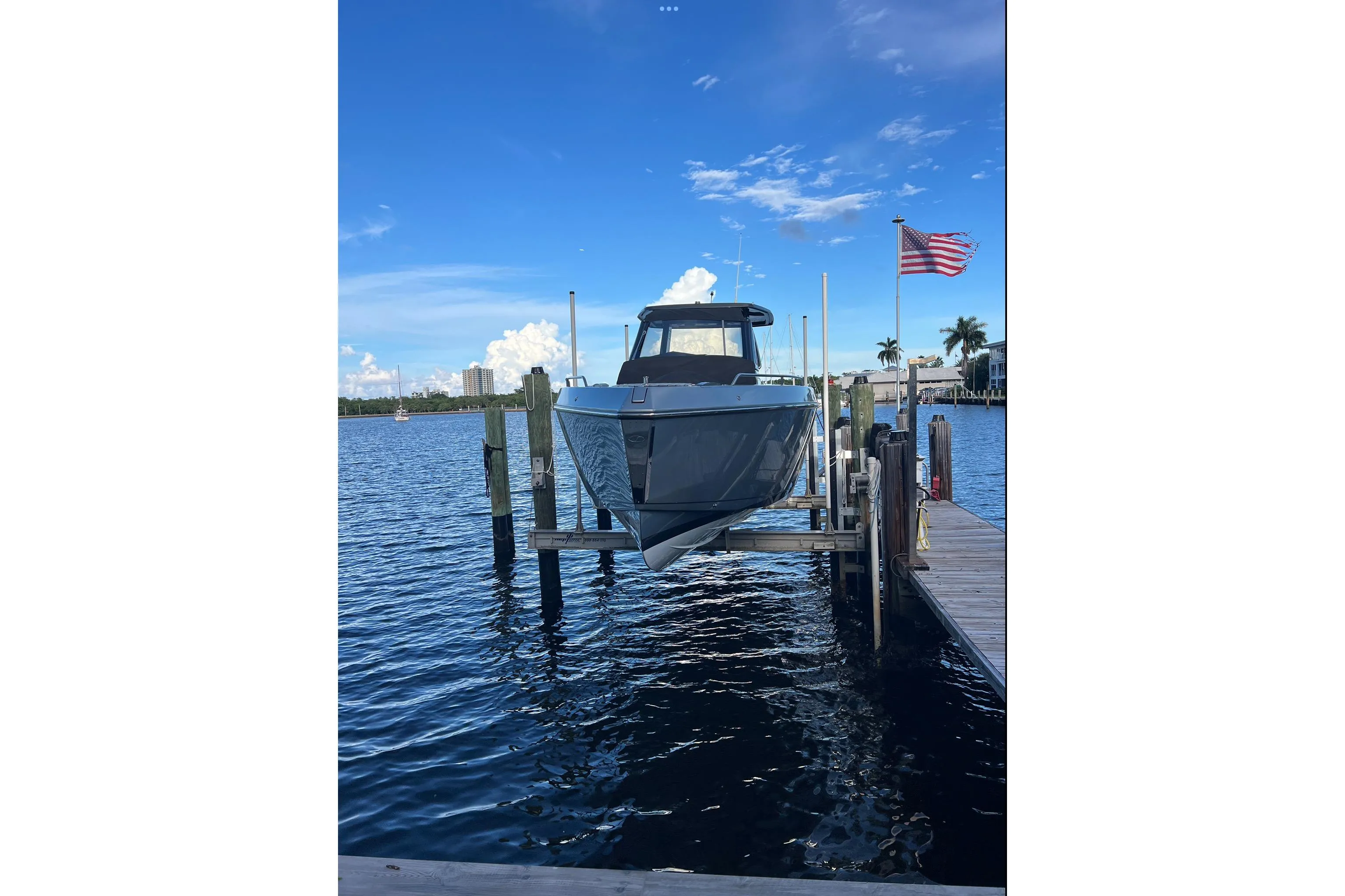 2023 Schaefer V33 boat docked on a lift, with American flag and blue sky.