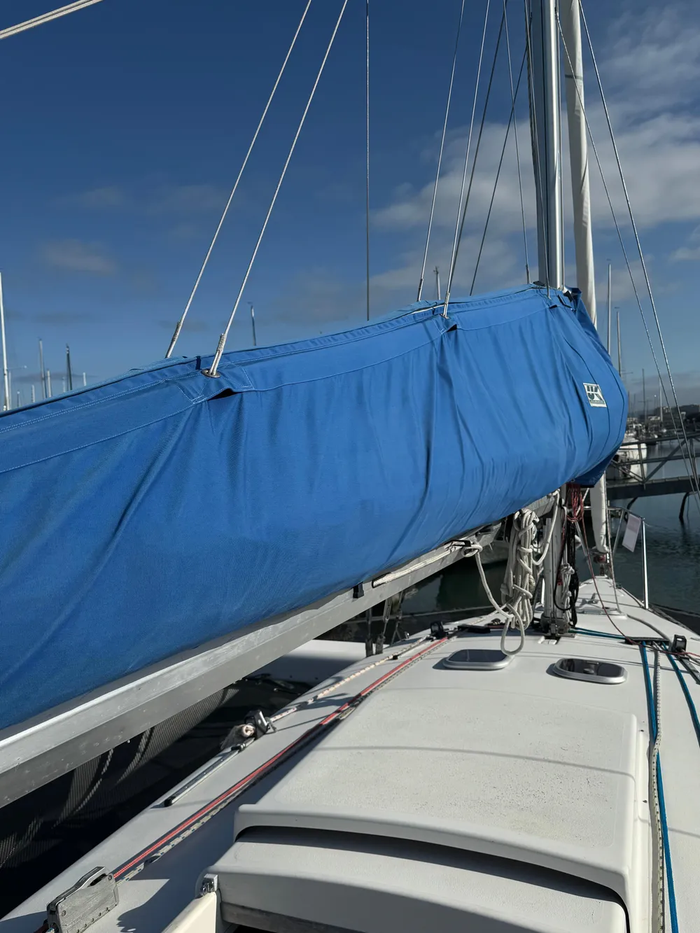 Sailboat deck with blue sail cover, Corsair F-31, 1996 model, under clear sky.
