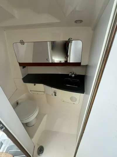 T-party Yacht Photos Pics Compact bathroom in 2012 Everglades LX 350 boat with sink, toilet, and mirror.