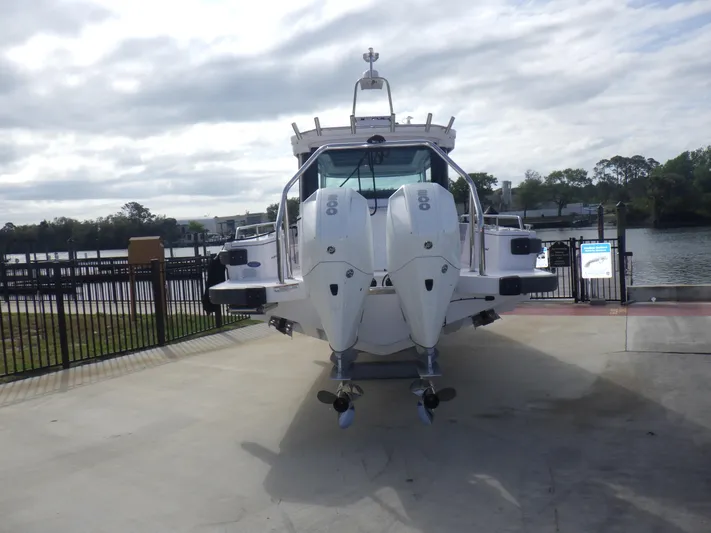  Yacht Photos Pics 2021 Axopar 28 CABIN boat with dual outboard engines, docked near a scenic waterfront.