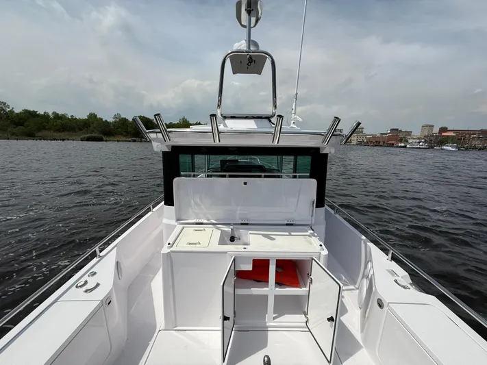  Yacht Photos Pics 2021 Axopar 28 CABIN boat on water, open storage compartments, clear sky background.