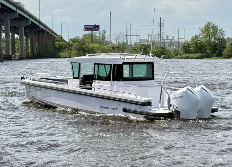  Yacht Photos Pics 2021 Axopar 28 CABIN boat cruising on a river near a bridge.