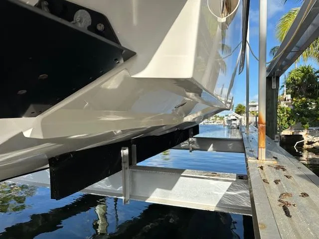  Yacht Photos Pics 2023 SeaVee 370z boat on lift, dockside view with clear water and palm trees.