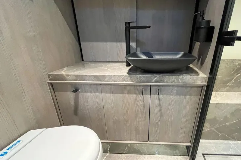  Yacht Photos Pics Modern bathroom interior of 2021 Cranchi A46 Luxury Tender with sleek black sink and marble countertop.