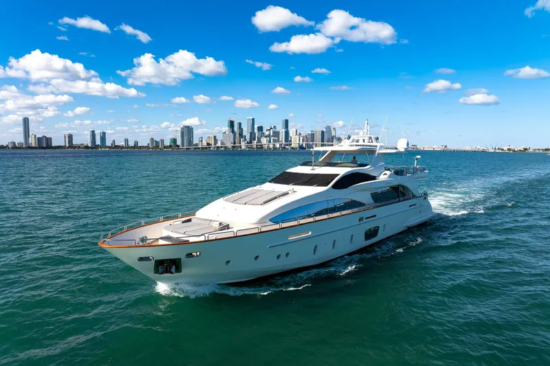 Babieca Yacht Photos Pics Luxurious 2005 Azimut 105 yacht cruising near a city skyline under a clear blue sky.